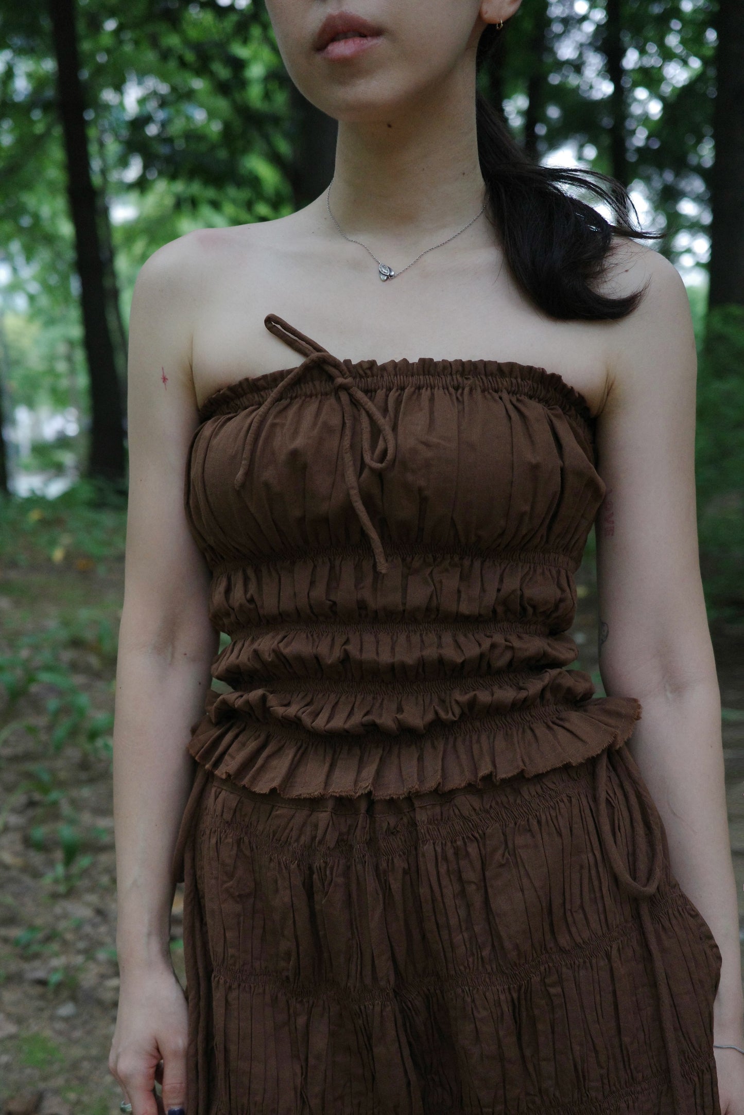 woman wearing in a brown tube top standing in a forest