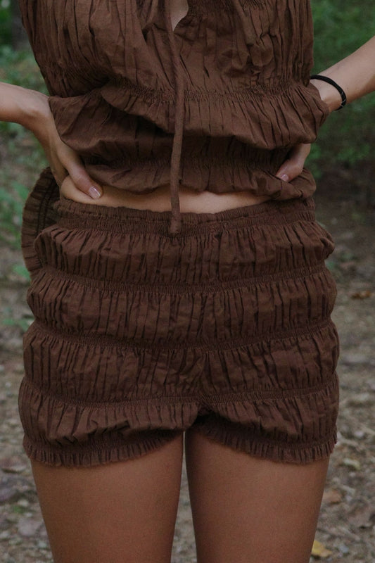 Brown textured outfit with shorts and top on a blurred natural background