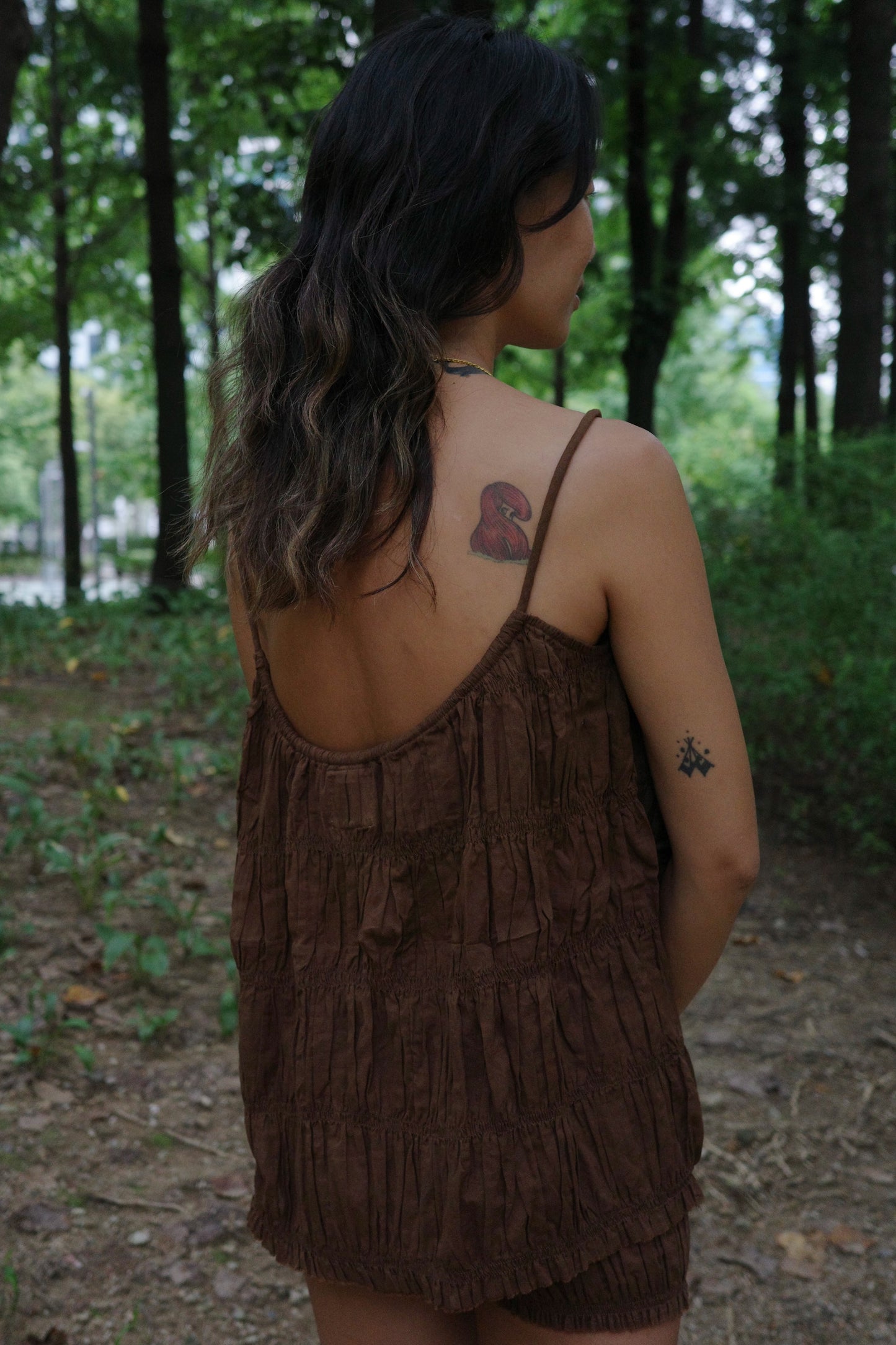 Woman in a brown string top standing in a forest