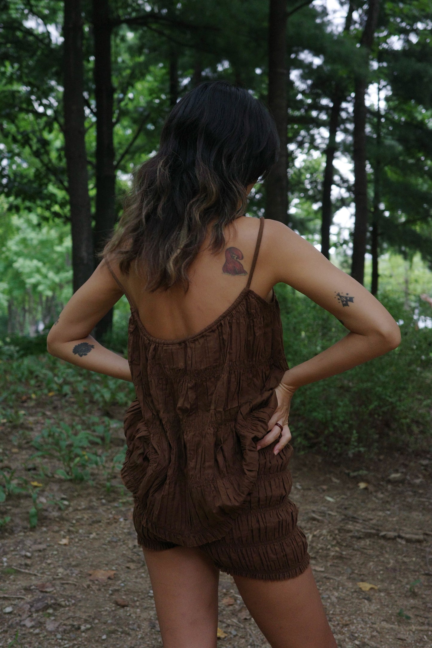 Woman in a brown ruffle top and short standing in a forest