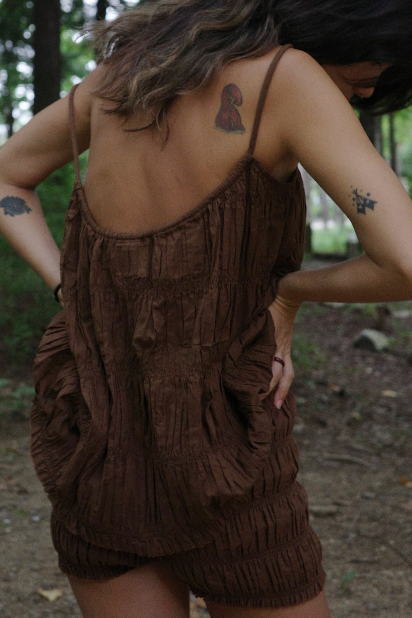 Person wearing a brown fringed top in a forest setting
