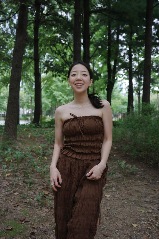 woman smiling in a brown tube top standing in a forest 