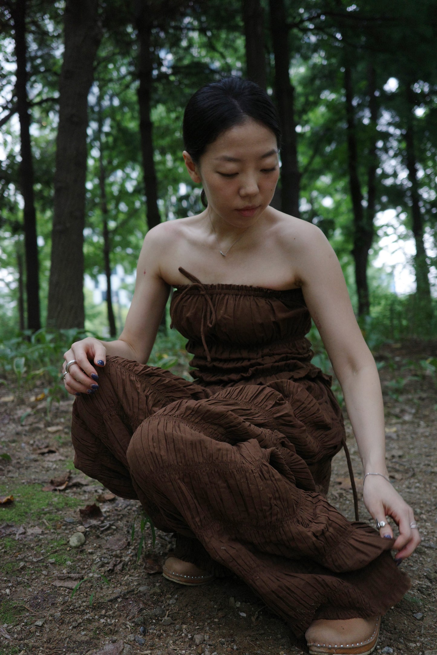 woman wearing in a brown outfit sitting in a forest 