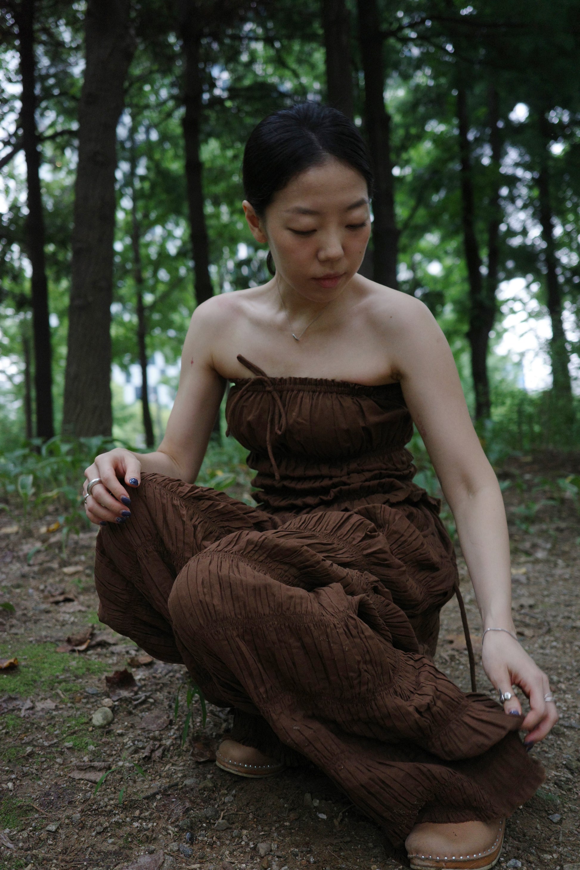 woman wearing in a brown outfit sitting in a forest 